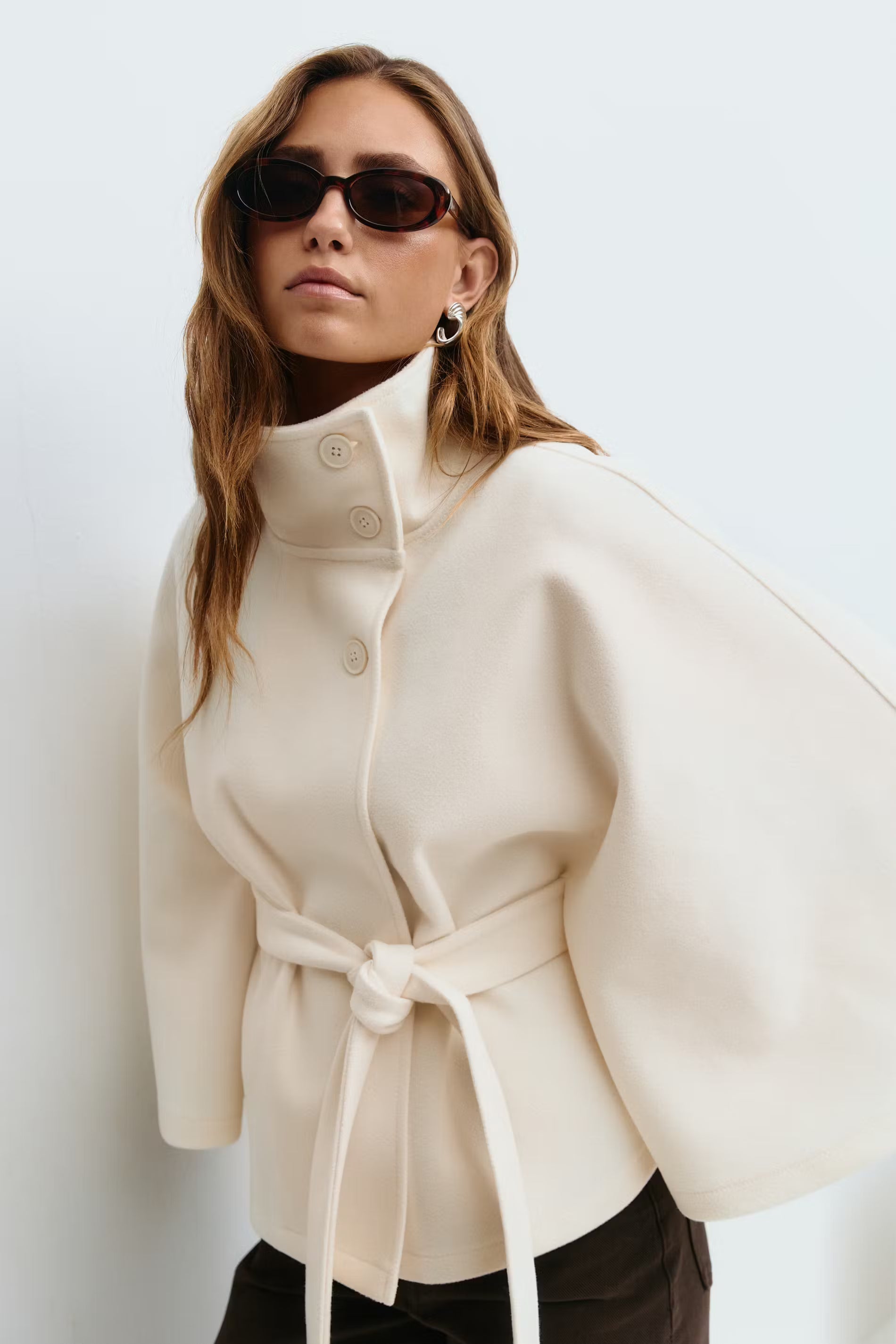Cape coat with high collar and belted waist in beige, front view