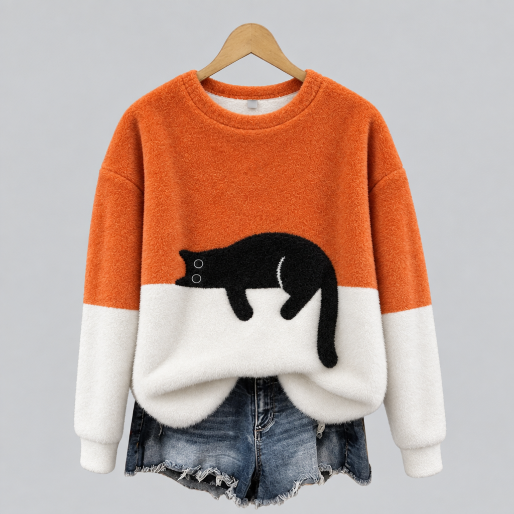 Orange plush fleece jumper with sleeping cat print on a hanger, styled with denim shorts