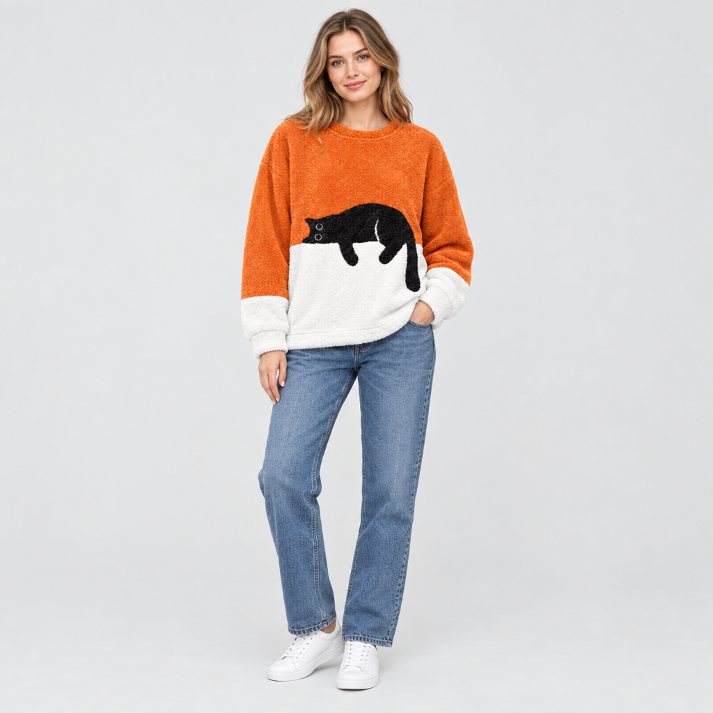 Model wearing orange plush fleece jumper with sleeping cat print, styled with jeans and white trainers