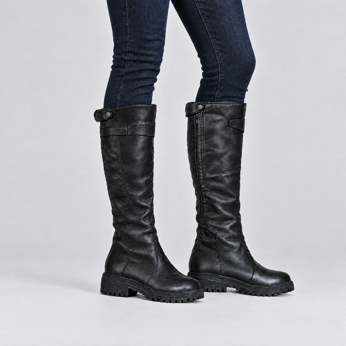 Black knee high boots worn with slim jeans tucked in